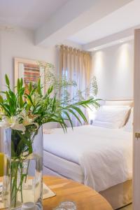 约阿尼纳维列尔民尼别墅旅馆的一间卧室配有一张床,一个花瓶摆放在桌子上