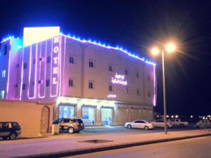 塞卡凯Lara Al Jawf Hotel Apartments的一座在晚上有灯的大建筑