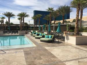 拉斯维加斯签名豪华套房国际酒店的一个带椅子和遮阳伞的游泳池以及棕榈树