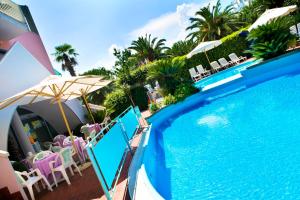 圣贝内代托-德尔特龙托地中海公寓酒店的毗邻度假酒店的带椅子和遮阳伞的游泳池