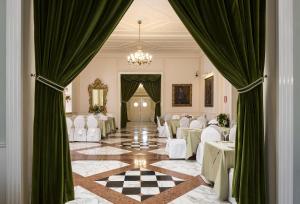 廖洛泰尔梅泰尔梅大酒店的宴会厅配有白色的桌子和绿色的窗帘
