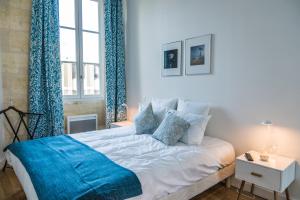 波尔多波尔多传统公寓的卧室配有一张带蓝色窗帘的大型白色床