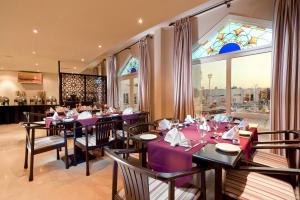 索哈尔艾瓦迪酒店 的餐厅设有紫色桌椅和彩色玻璃窗