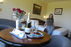 肯图巴高山汽车旅馆的坐在酒店房间床上的女士,带一瓶香槟