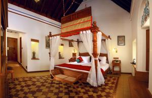 Kānādukāttān池达巴瑞维拉斯度假村 - 豪华遗产度假胜地的一间卧室,卧室内配有一张天蓬床