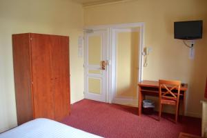 埃夫勒格兰德酒店的一间卧室配有一张床、一张书桌和一台电视