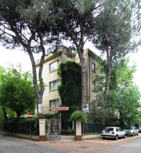 里乔内加尔尼野餐酒店的一座有树木和汽车停在前面的建筑