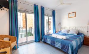 锡切斯锡切斯欧拉公寓酒店的一间卧室配有一张蓝色窗帘的床和一个阳台