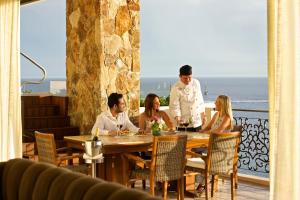 卡波圣卢卡斯格林索尔马天涯度假酒店和Spa中心的一群人坐在餐馆的桌子旁