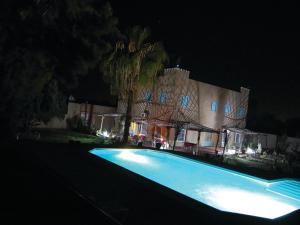 Oulad TeïmaGite Souss的一座游泳池,在晚上在建筑物前