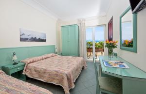 卡普里大乔治酒店的酒店客房设有两张床、一张书桌和一个窗户。