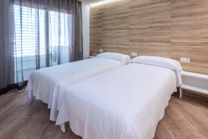 坎布里尔斯Mònica Mar Apartments的带窗户的客房内的两张床,配有白色床单