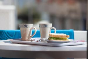 埃斯普霍斯阿莱曼尼亚旅馆的夹三明治的盘子和桌子上的两个杯子