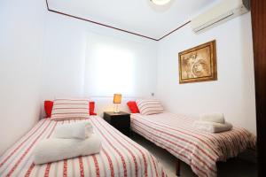 坎布里尔斯La Torre - Villa Rosamar Beach的白色客房的两张床,红色和白色条纹