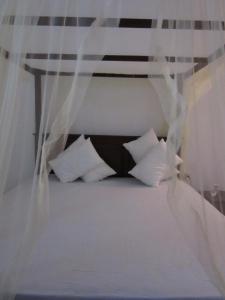 坦加拉Sanderling Silent Beach Cabanas的一张带白色枕头和天蓬的床