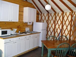 Harden Flat约塞米蒂国家公园湖5号山丘圆顶帐篷的厨房配有白色橱柜、桌子和冰箱。
