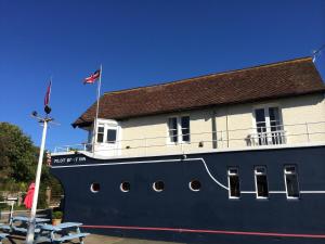 本布里奇The Pilot Boat Inn, Isle of Wight的一条蓝色和白色的大船,上面有一座建筑