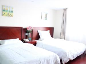 金山区格林豪泰上海市金山万达广场龙翔路快捷酒店的配有白色床单的客房内的两张床