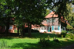 克洛斯特Ferienwohnung Hiddensee Hitthim的红屋顶,树木和草地的房子