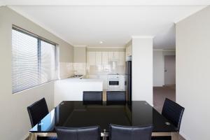 堪培拉品尼克公寓式酒店的厨房配有黑色餐桌和椅子