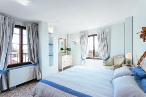 威尼斯泻湖景豪华公寓酒店的白色卧室设有大床和窗户