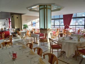圣克洛德全景餐厅朱拉酒店的餐厅设有白色的桌椅和窗户。