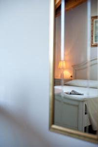 萨韦纳河畔圣拉扎罗卡塞勒酒店的卧室的镜子反射,卧室配有一张床