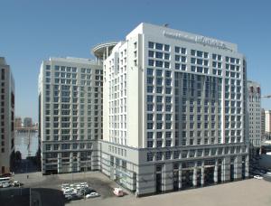 麦地那麦地那瑞享酒店的停车场内有车的高高的白色建筑