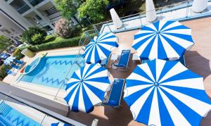 比比翁公主公寓酒店 的一组蓝色和白色的遮阳伞,位于游泳池旁