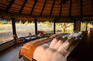 奥奇瓦龙戈Okonjima Luxury Bush Camp的一张大床,位于带大窗户的房间里