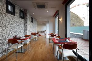 奥维多埃玛奇斯桃酒店的餐厅设有红色的桌椅和砖墙
