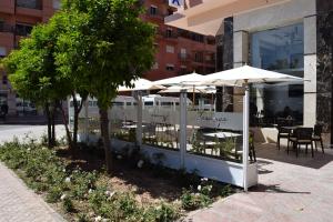 马拉喀什特雷加Spa酒店的大楼前的餐厅,配有桌子和遮阳伞
