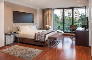 波哥大爵士公寓酒店的一间卧室配有一张床、一张书桌和一个窗户。
