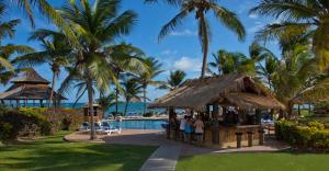 维约堡Coconut Bay Beach Resort & Spa All Inclusive的一群人站在一个酒吧旁边,在游泳池边