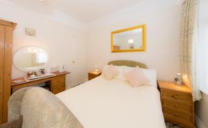 伯恩茅斯Shoreline Accommodation的卧室配有白色的床和镜子