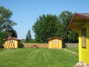 KolkjaKolkja Holiday Centre的一座院子,两栋黄色的小建筑和游乐场