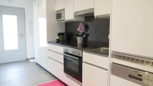 格拉茨Apartement Maria Trost的厨房配有白色橱柜和炉灶烤箱。