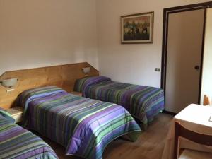 Lentate sul Seveso阿菲塔朱迪西旅馆的配有带条纹床单的酒店客房内的两张床
