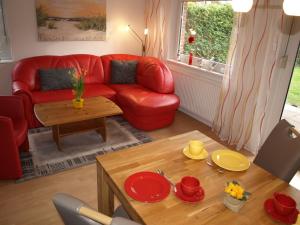 博尔滕哈根Urlauberdorf 62a的客厅配有红色的沙发和桌子