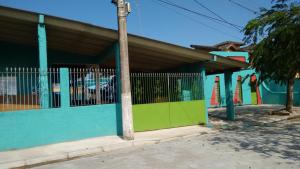 卡拉瓜塔图巴Suítes Recanto Renascer的蓝色和绿色的建筑,前面有一根杆
