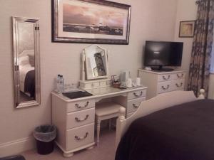 北费利比Eastdale Bed and Breakfast的一间卧室配有一张桌子、一台电视和一面镜子