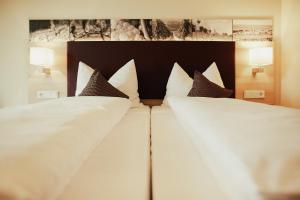 弗隆海姆Meyerhof - Weingut, Vinothek & Gästehaus的一张配有白色床单和棕色枕头的大床