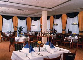 舍纳贝克多米希尔舒贝克酒店的用餐室配有白色桌椅和桌子。
