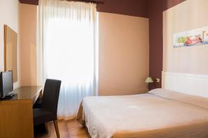 佛罗伦萨全景酒店的一间卧室配有一张床、一张书桌和一个窗户。