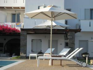 帕罗奇亚Roses Beach的游泳池畔的白色遮阳伞和椅子