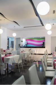 蒙特里亚巴罗卡酒店的餐厅设有白色的桌椅和色彩缤纷的墙壁