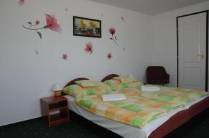 贝拉帕法瓦Bélkő Panzió的一间卧室配有一张带五颜六色棉被的床