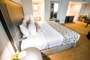 马那瓜马那瓜皇冠广场酒店的酒店客房配有一张带白色床单和枕头的大床。