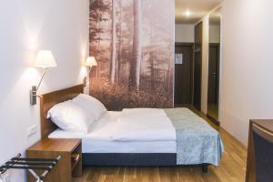 维也纳贝内迪修道院旅馆的卧室配有一张床,墙上挂有绘画作品