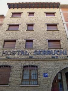 特鲁埃尔Hostal Serruchi的砖砌的建筑,上面有标志